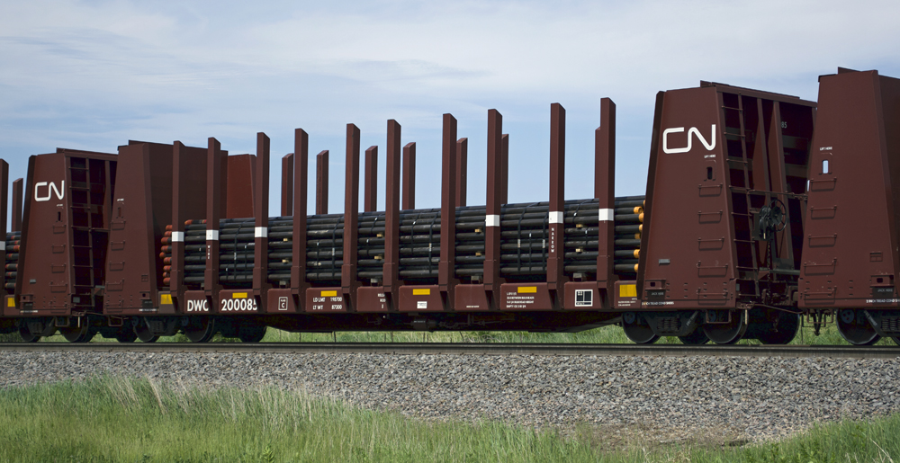 Color photo of bulkhead flatcar with pipes.