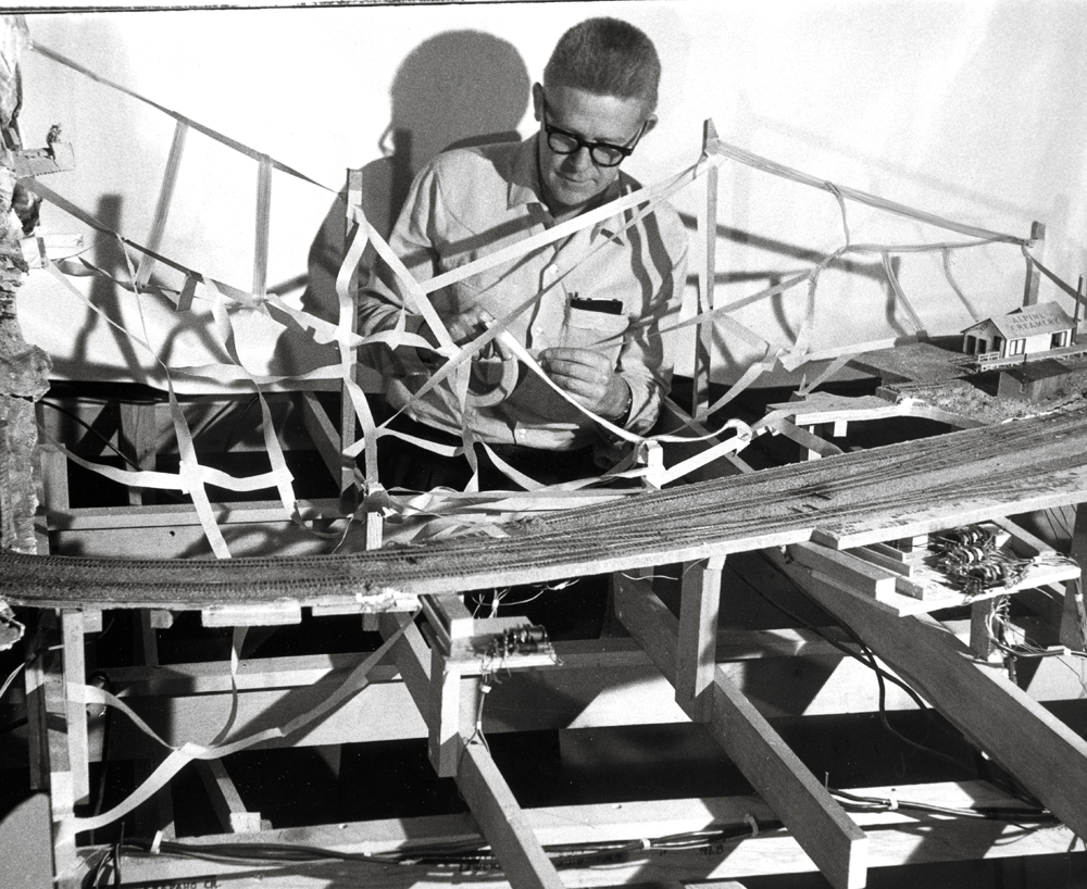 vintage photo of man next to partially built model train layout