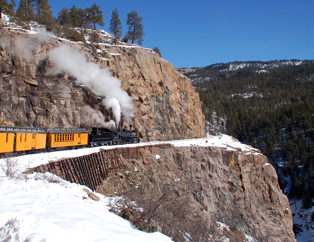 black steam train going through mountains
