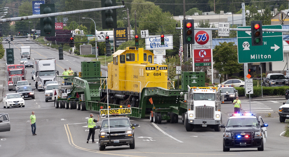 yellow locomotive being transported on truck