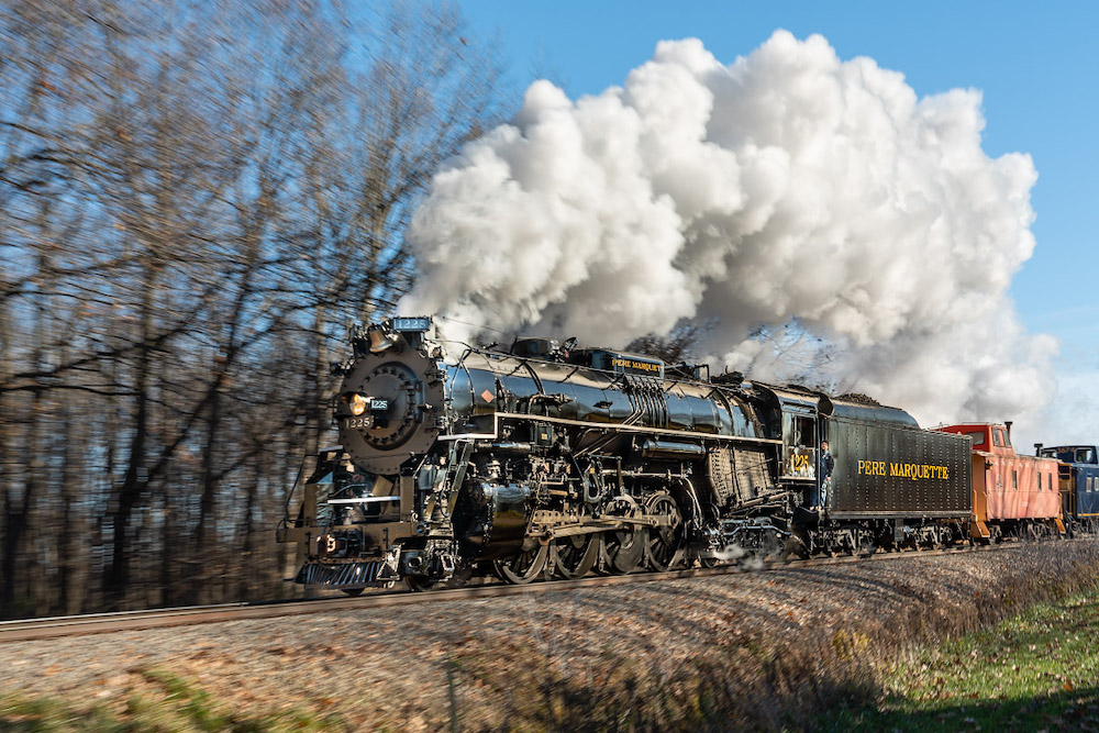 Steam locomotive rounding curve on a sunny day.