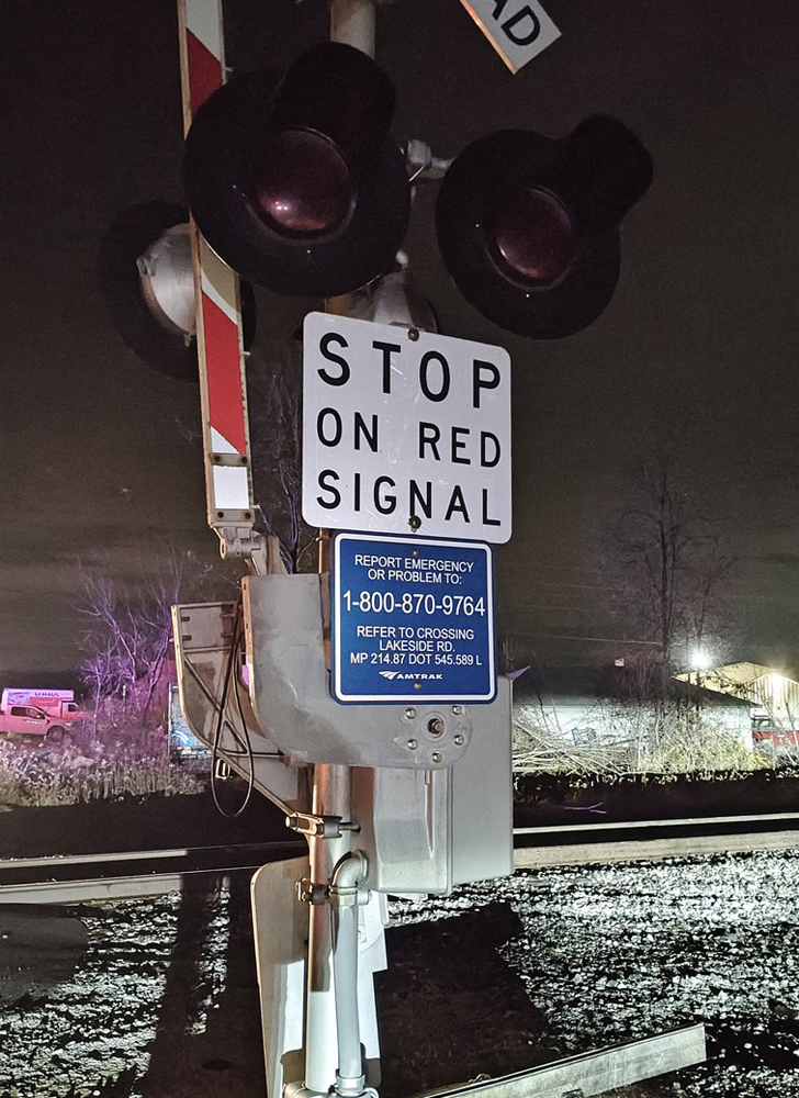 Sign on crossing gate with 1-800 phone number for emergency notification