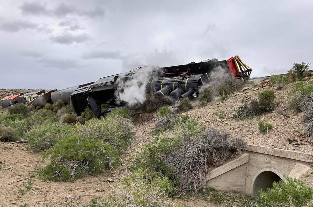 Steam locomotive on its side in desert landscape