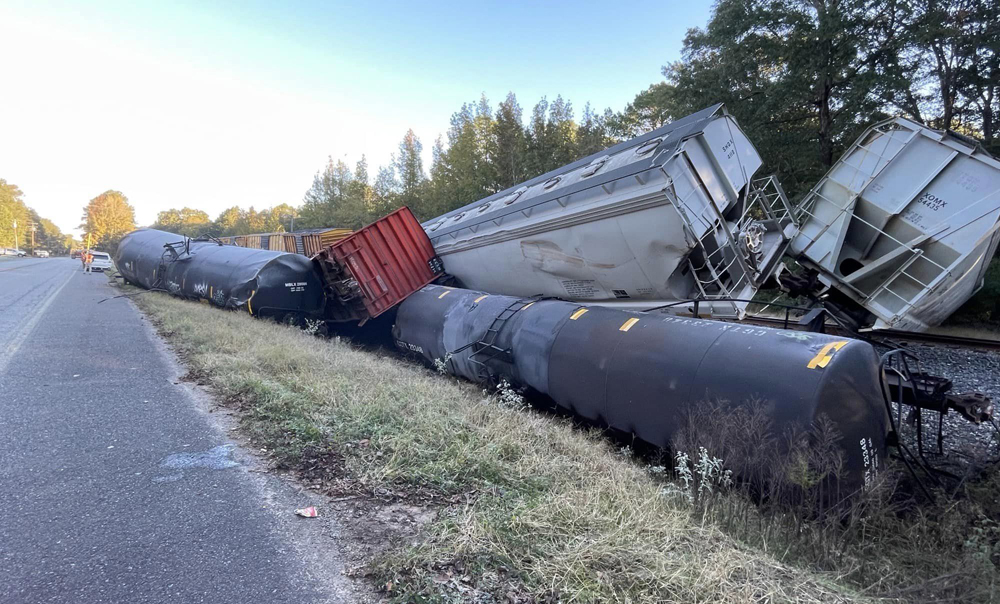 Stack of derailed freight cars next to highway