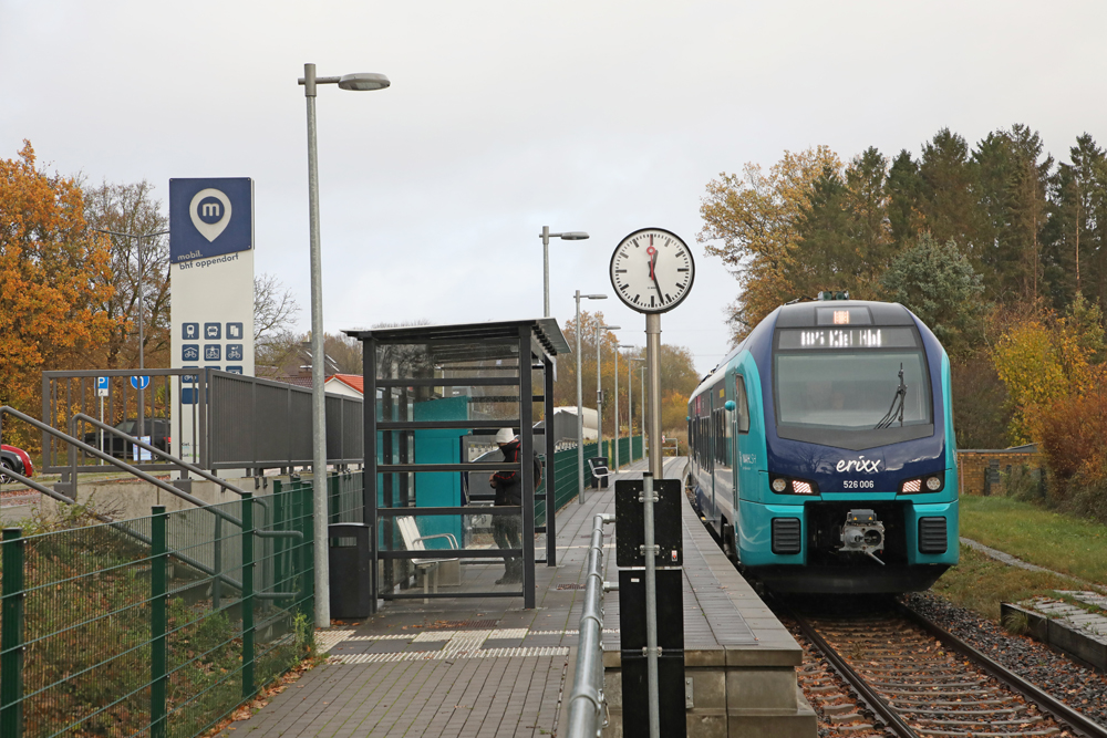 Blue multiple-unit passenger train at simple shelter station and platform