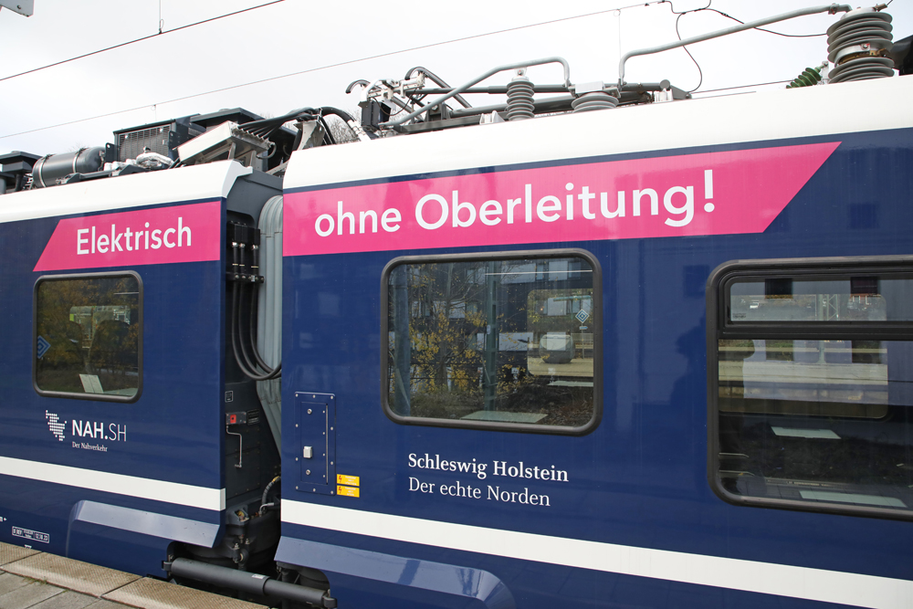 Side view of part of battery-electric multiple-unit passenger train with closeup of message in German
