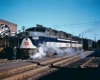 Man leans out window on blue-and-gray Wabash locomotives with passenger train 