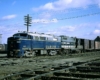 Two blue-and-gray diesel Wabash locomotives on freight train crossing railroad tracks