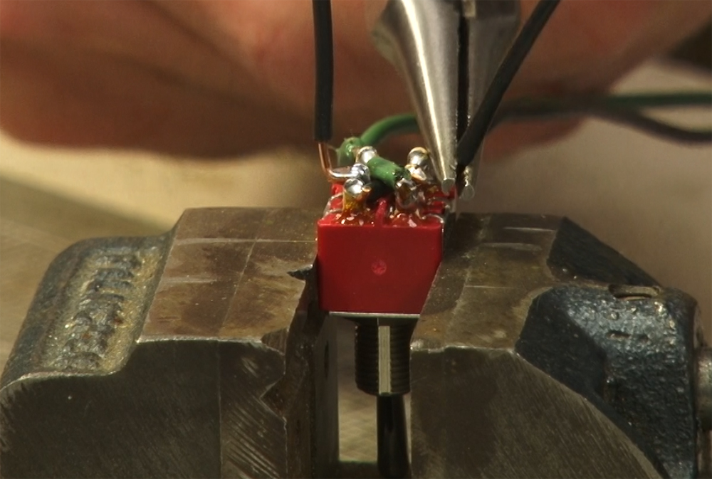 Photo of pliers bending wire on a switch.