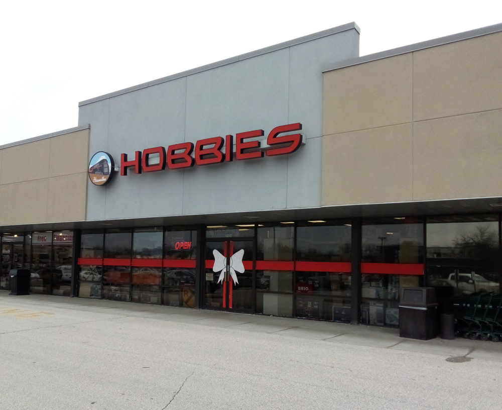 Color photo showing front of a hobby shop located in a shopping plaza. 