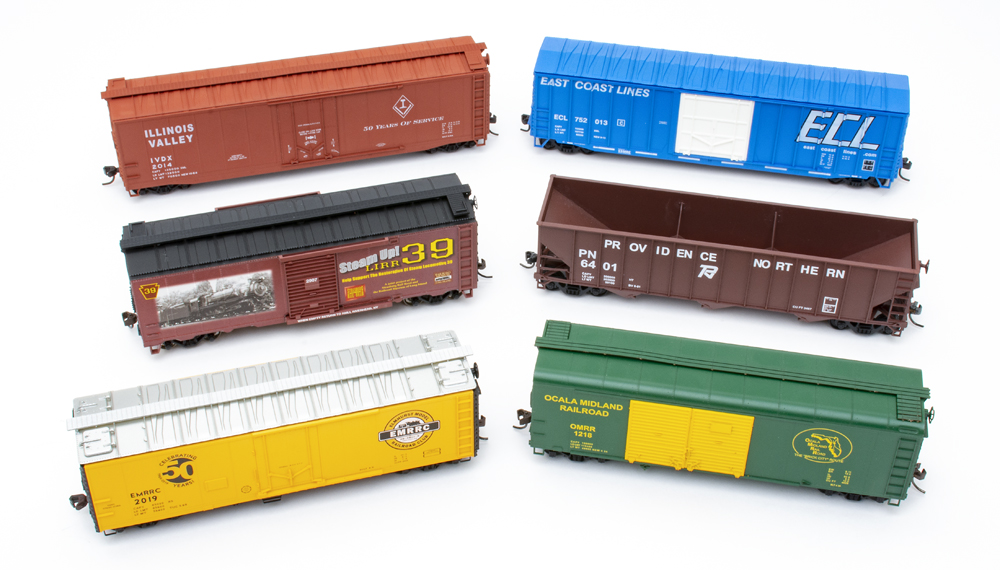 Color photo of six HO scale freight cars decorated for various model railroad clubs.