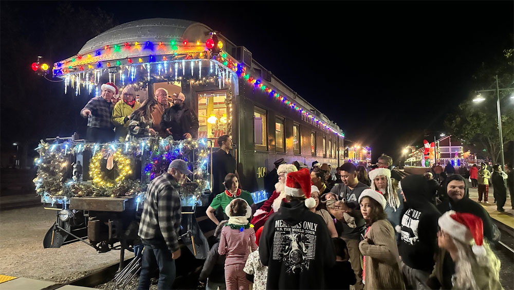 group standing by holiday-themed train with Santa