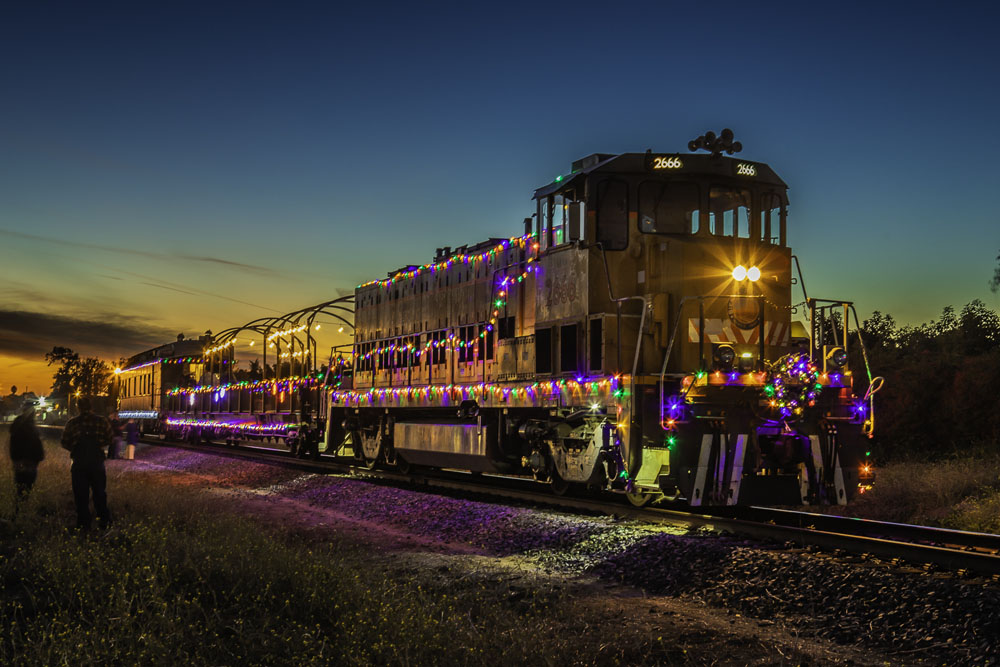 train wrapped in holiday lights on tracks