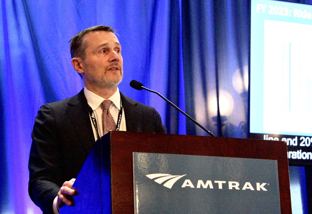 Man at podium with Amtrak logo
