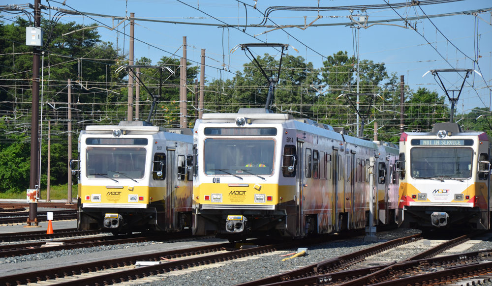 Yellow and white light rail trainsets in yard