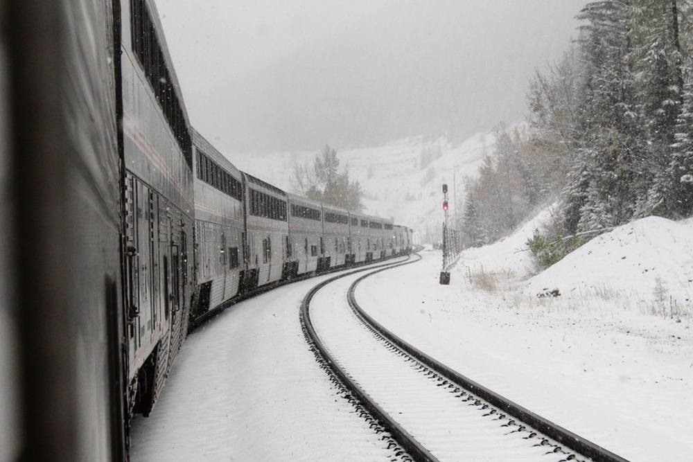 Passenger train rounds curve in mountains in photo from onboard