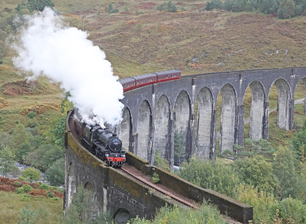 Steam-powered passenger train in UK on curved trestle