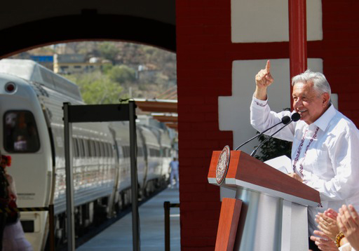 Man speaking at podium with train in background