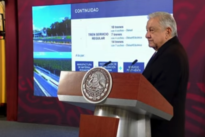 Man at podium with video screen in background