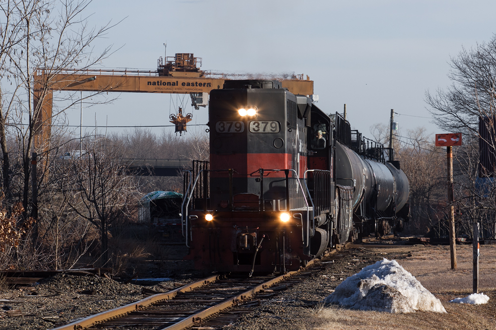 Gray and orange locomotive with train on wavy, jointed-rail track