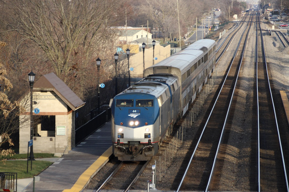 Passenger train on three-track main passes commuter station