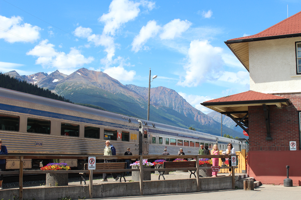 Passenger train at station with mountains in background