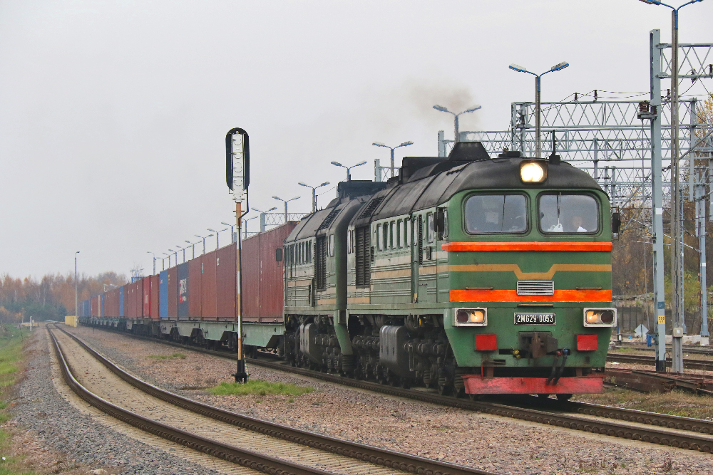Green European locomotive pulling a container train. 