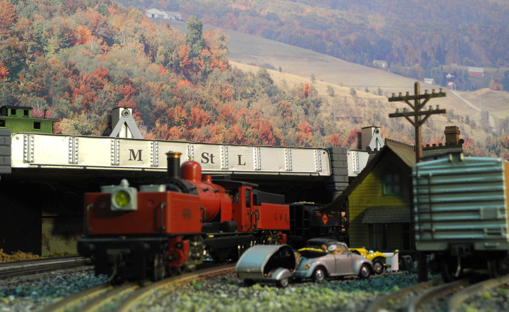 red model engine next to bridge on layout