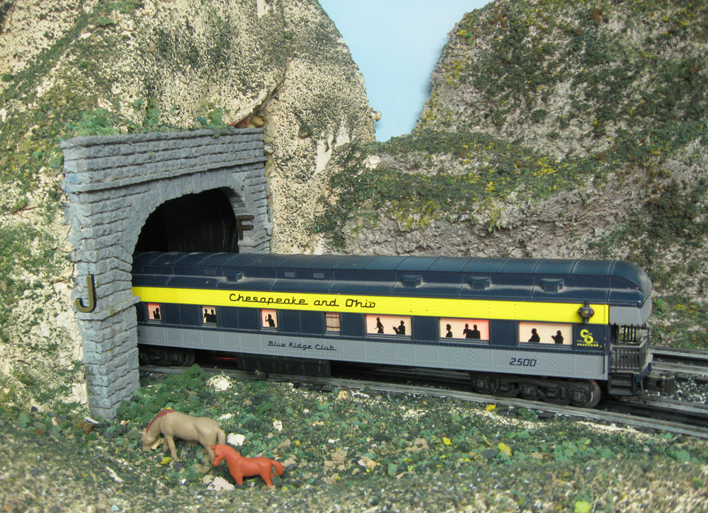 blue and yellow model train enters tunnel
