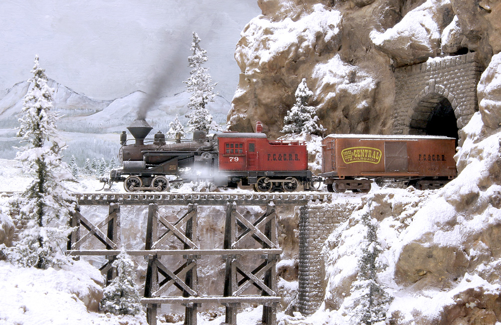 A geared steam locomotive leads a train onto a wood trestle covered with snow