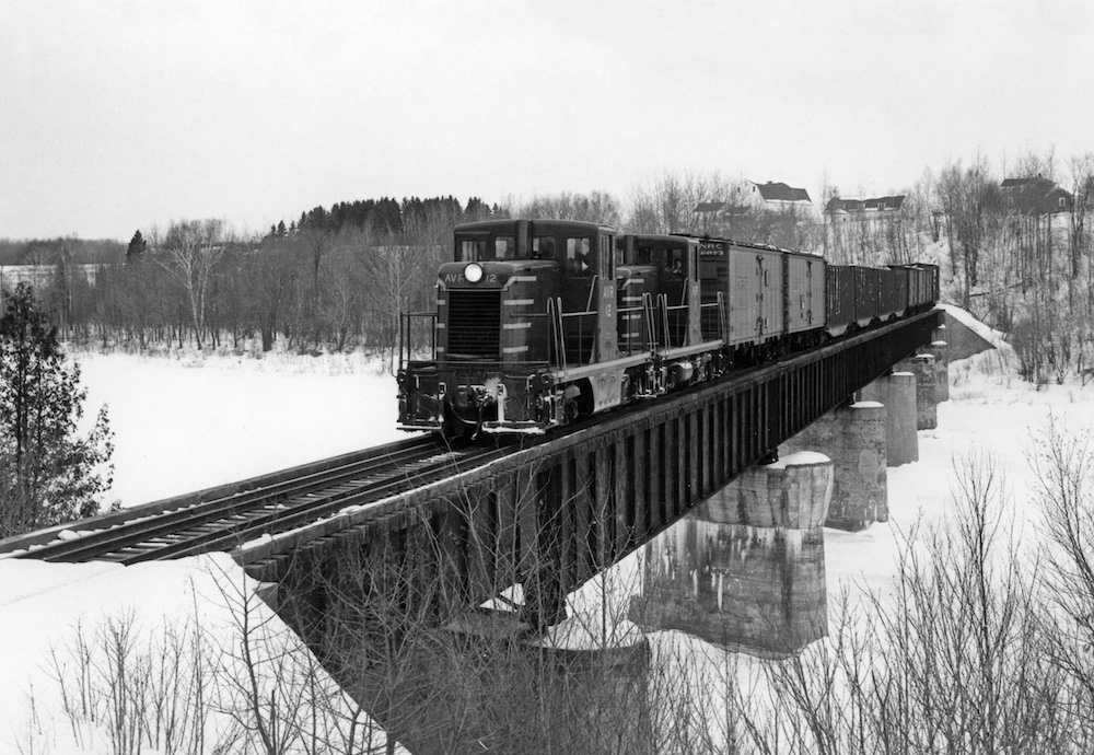 Freight train crosses river on a winter day.