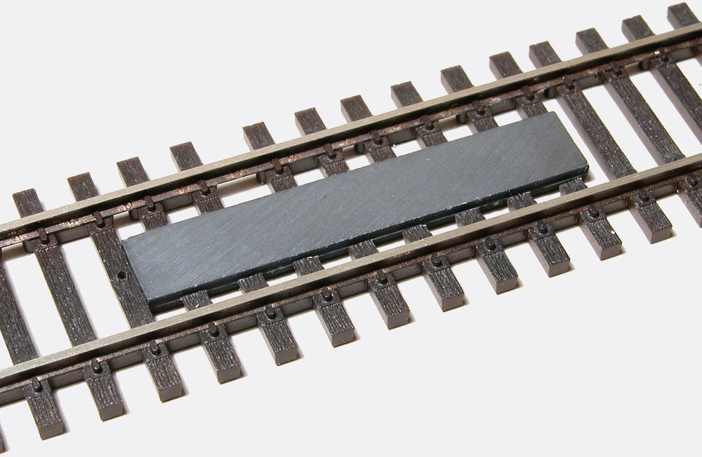 Color photo showing HO scale between-the-rails-magnet.