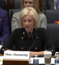 Woman seated at table in front of microphone.