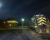 night shot of locomotive passing a building