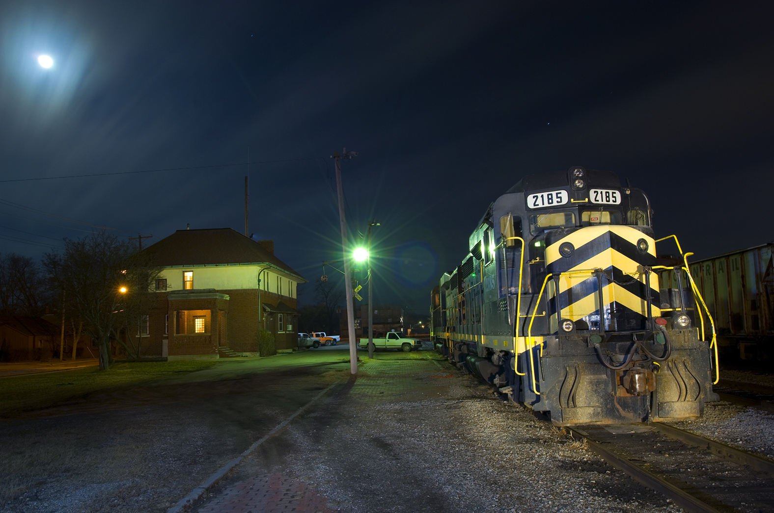 night shot of locomotive passing a building