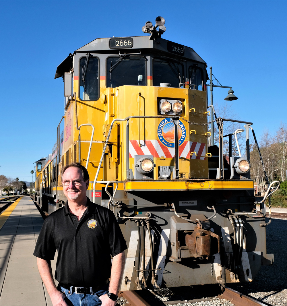 man in black shirt in front of yellow locomotive