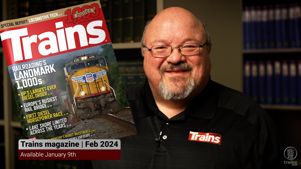 man with glasses holding issue of Trains