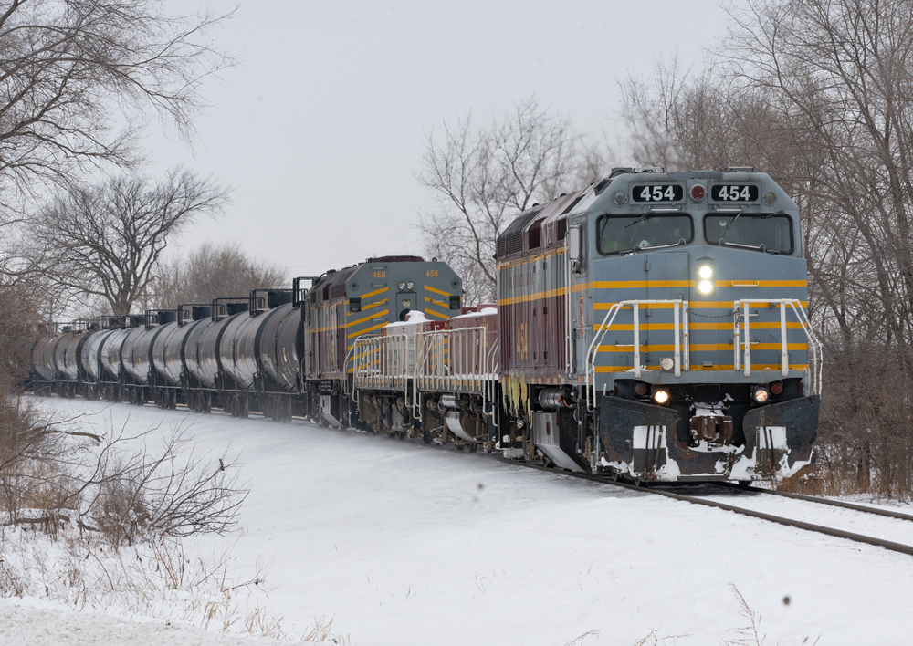 Two silver and yellow locomotives on track with snow