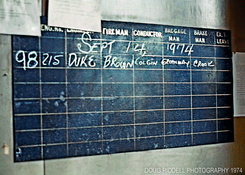A black chalkboard spells out the names of the crew assigned to an Amtrak train in white chalk