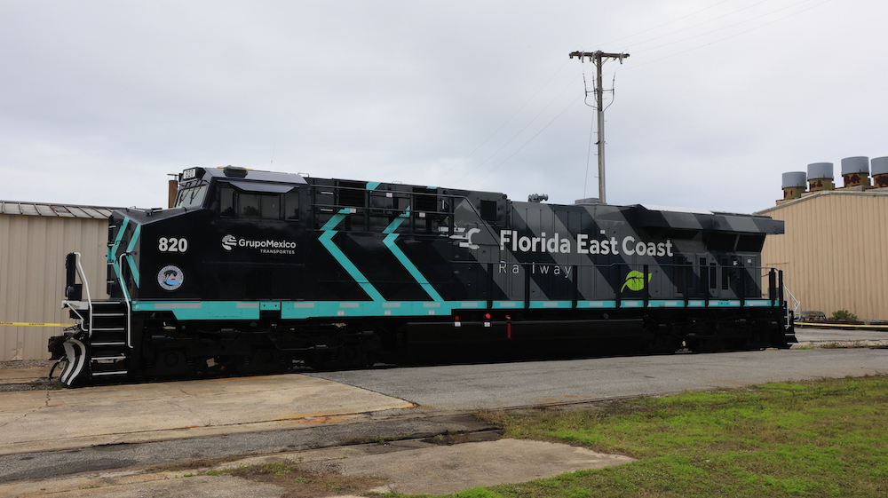 Repainted diesel locomotive sits outside of shops.