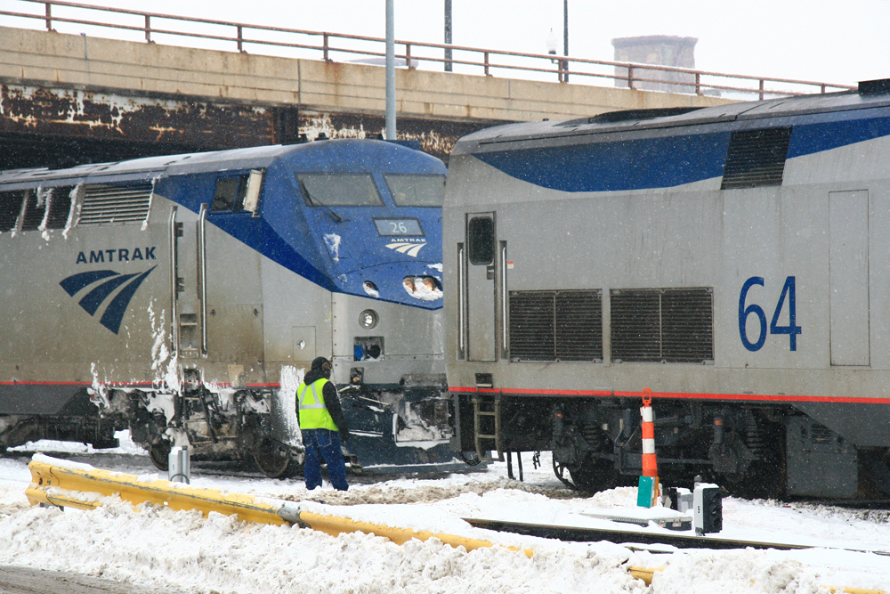 Workers attending to locomotives in snow.