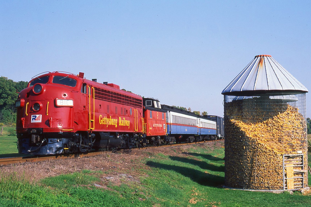 Red F-unit with train including caboose, two coaches, and a boxcar