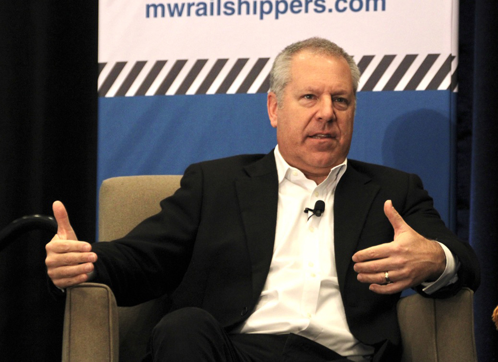 Man in black coat and white shirt gesturing while speaking