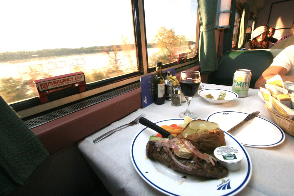 Dinner on table in dining car with river visible outside window