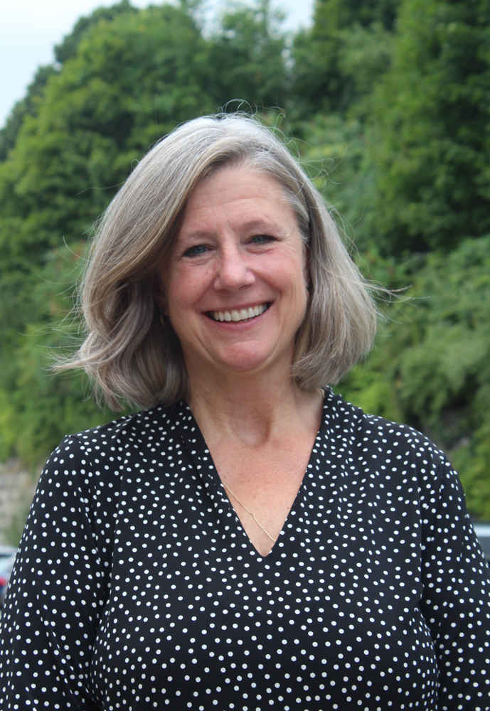 Smiling woman outdoors with trees as backdrop