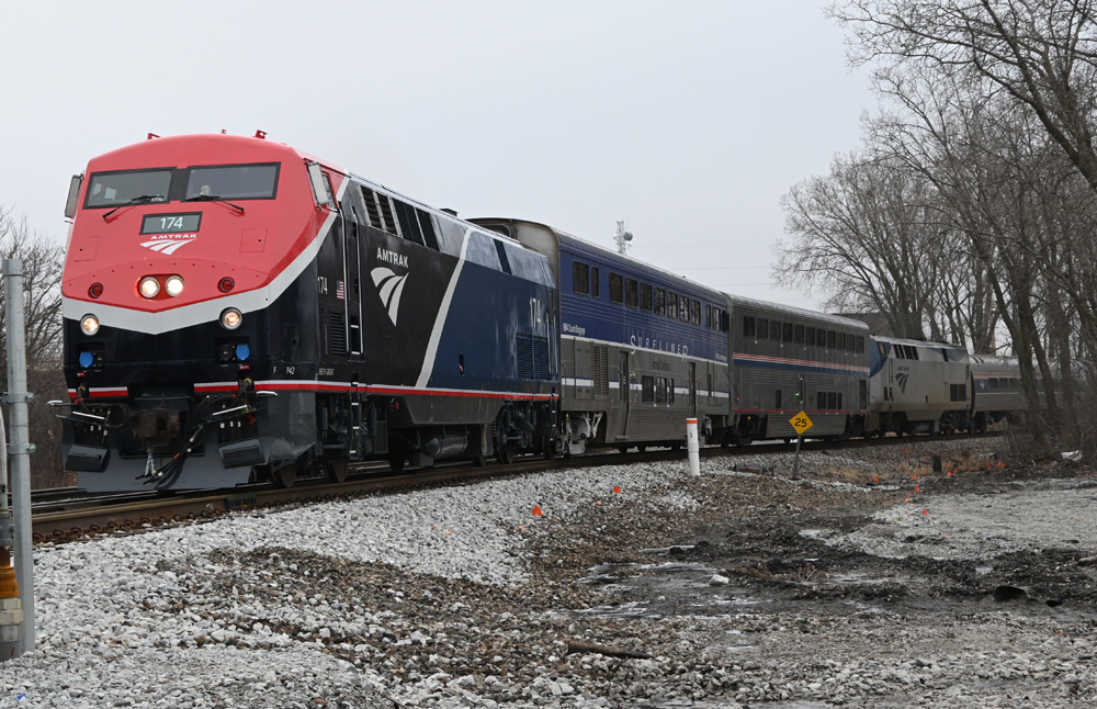 Locomotive with red and two tones of blue paint leading passenger train