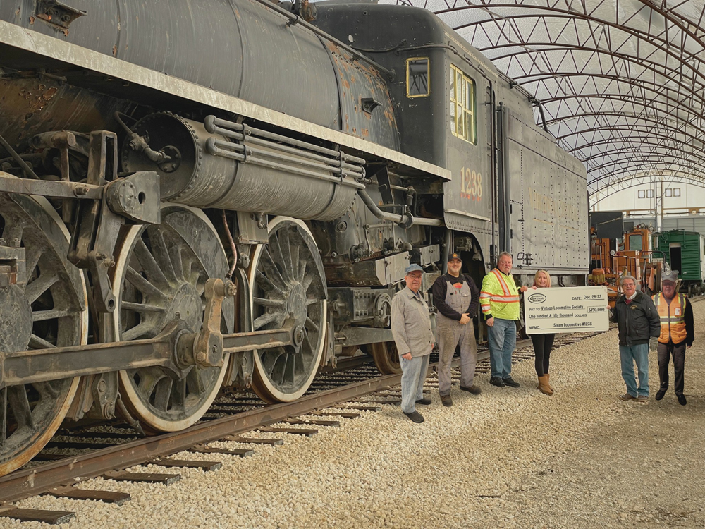 Men with oversized check next to steam locomotive