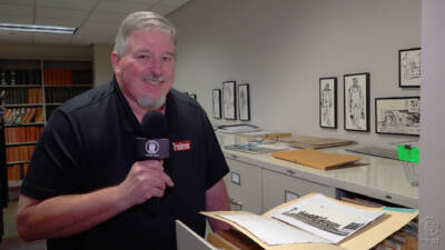 Man looking a a file folder with black and white photographs.