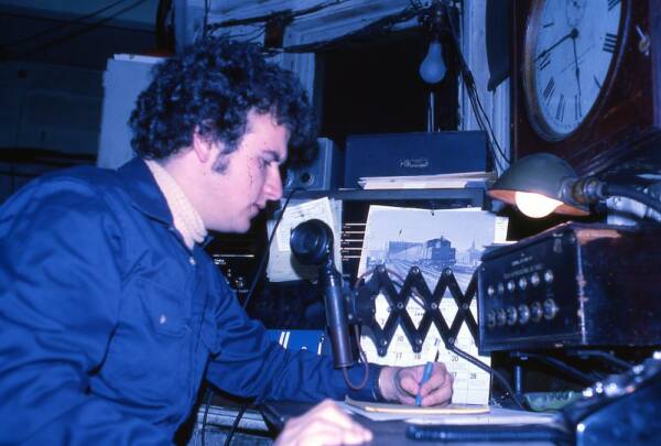 Man using old-fashioned radio microphone in a cluttered office