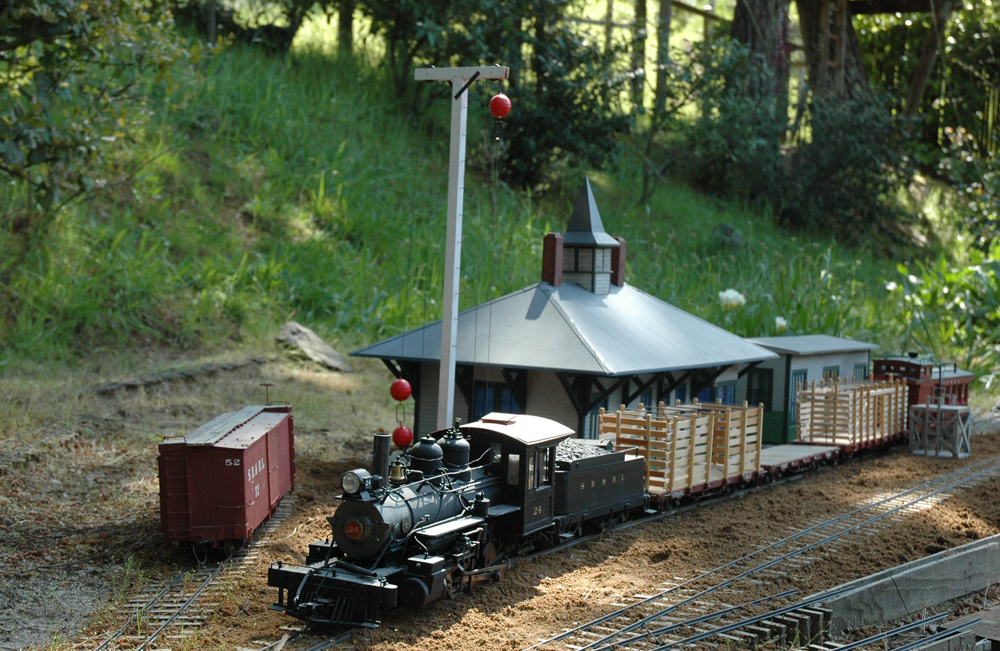 scene on garden railway with locomotive, station, and boxcar; Jim Providenza—garden railway edition